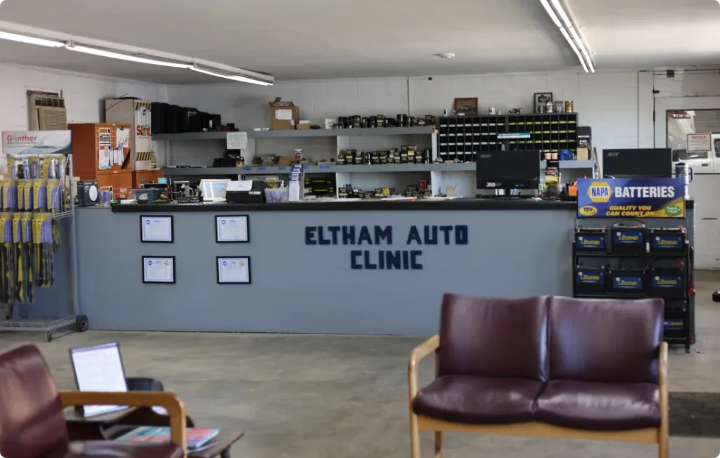 careers, auto repair in West Point, VA at Eltham Auto Clinic, Reception area of an auto repair shop with a counter labeled Eltham Auto Clinic, shelves of automotive parts behind, and chairs for waiting customers in the foreground. NAPA Batteries display is visible to the right.
