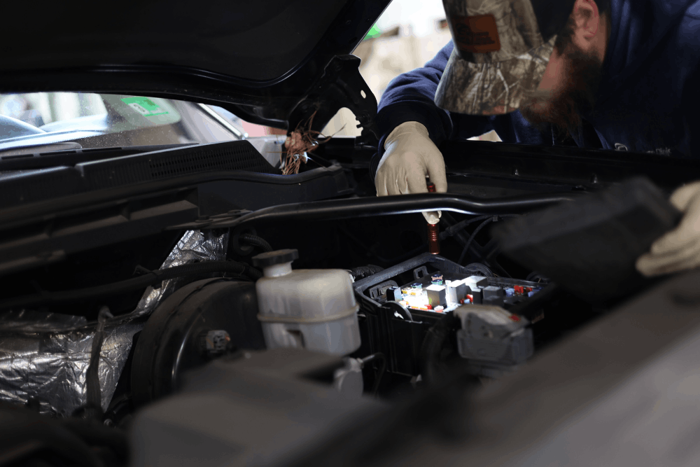 Vehicle maintenance, auto repair in West Point, VA at Eltham Auto Clinic. Image of a technician inspecting the fuse box and electrical components under an open hood to support reliable vehicle operation.